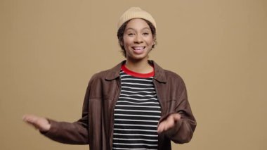 Kıvırcık saçlı kendine güvenen kadın konuşmacı, kameradaki bir şeyi anlamlı el hareketleriyle açıklıyor. Çevrimiçi dersler, sosyal medya içeriği, vloglama, dersler veya webinarlar