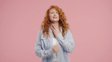 Genç ve güzel bir kadının yarası var. Pembe Stüdyoda Boğazı Şişmiş Hasta Kadın. Anjin. Genç kız acı hissediyor, acı çekiyor. Mevsimsel grip, soğuk algınlığı. Yüksek kalite 4k 