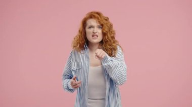 Stres ve öfke içinde bir kadın, saldırganlıkla tehdit ediyor, bağırıyor ve pembe kameraya bakıyor. Öfkeli kızıl saçlı Amerikalı kadın. Çatışma, tartışma, stres, duygusal patlamalar. Yüksek kalite 4k görüntü