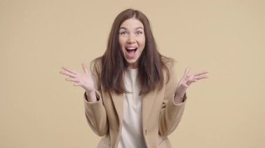 Etkilenmiş iş kadını, vay canına diyor. Takım elbiseli güzel kadın bej arka planda kameraya şaşırdı. Kârlı bir teklif..