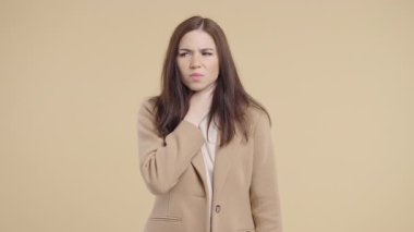 Genç ve güzel bir kadının yarası var. Bej Stüdyoda Boğazı Şişmiş Hasta Kadın. Anjin. Genç kız acı hissediyor, acı çekiyor. Mevsimsel grip, soğuk algınlığı. Yüksek kalite 4k 