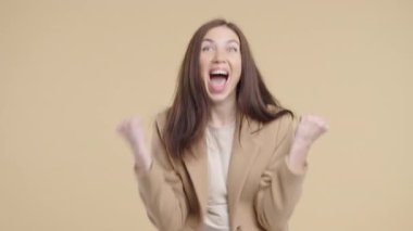 Kendine güvenen kahverengi saçlı kadın başarıyı enerjik bir yumruk pompası ve ışıltılı bir gülümsemeyle kutluyor. Başarı, duygusal kazanç, motivasyon, ilerleme, kadın gücü