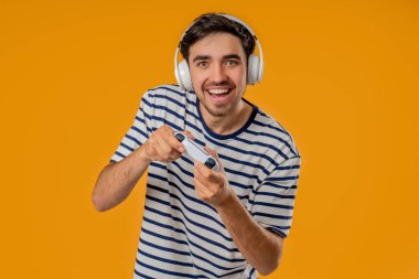 TV 'de video oyunu oynayan yakışıklı esmer adam sarı stüdyo arka planında joystick izole edilmiş. Modern teknolojiyi kullanarak. Yüksek kalite fotoğraf