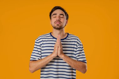 Sarı arka planda namaste 'de avuç içi dua eden genç adam. Adam birine arzularını tatmin etmesi için yalvarıyor, yardım ediyor, sınavda şans için dua ediyor. Yüksek kalite