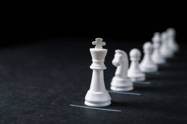 Kısıtlı çizgileri olan karanlık bir arkaplanda satranç taşları. Koronavirüs salgını sırasında sosyal uzaklık kavramı. Kuyruklardaki uzaklık.