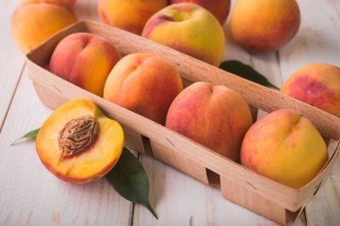 Beyaz ahşap masada sulu ve olgun şeftali meyveleri.