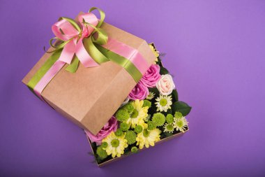 Mor arkaplanda çiçekler olan hediye kutusu