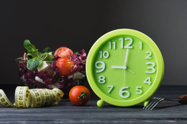 Domatesli cam kasede taze salata, peynirli peynir ve ahşap masada yeşil yapraklar. diyet arkaplanı