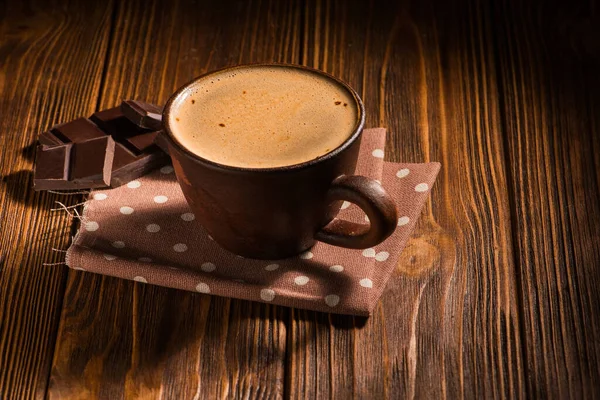 coffee cup with chocolate bar on napkin. rustic ventage style table