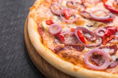 Tahta üzerinde salamlı, soğanlı ve pepperonili lezzetli pizza.