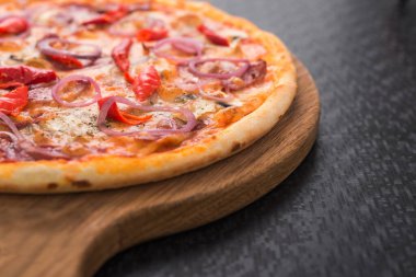 Tahta üzerinde salamlı, soğanlı ve pepperonili lezzetli pizza.