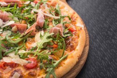 Siyah mutfak masasında prosciutto ve rogula soslu İtalyan pizzası.