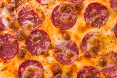 Siyah arka planda salam soslu sıcak pizza.