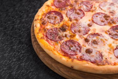 Siyah arka planda salam soslu sıcak pizza.