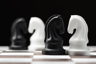 Satranç tahtasındaki satranç şövalyesi siyah arka planda.