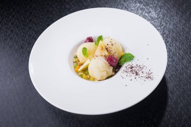 Meyveli şerbet buzu ve siyah arka planda beyaz tabakta nane.