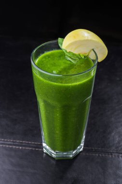 Siyah arka planda elma ve nane aromalı yeşil smoothie. Vejetaryen kokteyl bardağı.