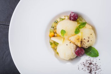 Meyveli şerbet buzu ve siyah arka planda beyaz tabakta nane.