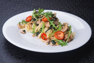 Beyaz tabakta domatesli ve mantarlı lezzetli makarna.