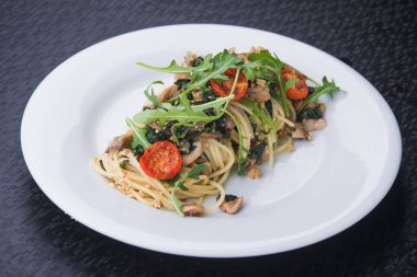 Beyaz tabakta domatesli ve mantarlı lezzetli makarna.