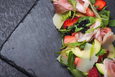 Çilekli lezzetli salata ve siyah üzerine jambon.