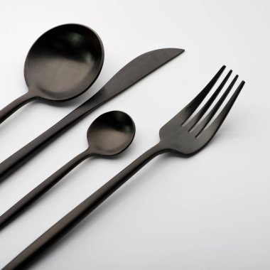 Siyah çatallı çatal takımı, beyaz arka planda bıçak ve kaşık.