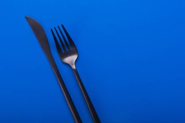 Bıçak ve çatal ahşap masada. Çatal bıçak takımı arka planda.