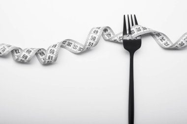 Diyet kavramı, siyah çatal ve ölçüm bandı beyaz arka planda izole edildi