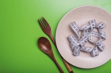 kilo verme konsepti. Çatallı, bıçaklı ve kaşıklı bir tabak.