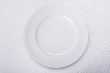 Ahşap arka planda boş seramik plaka. en üstteki görünüm