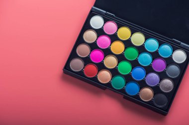 Pembe arka planda renkli kozmetik palet. güzellik makyajı 