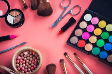 Pembe arka planda fırça tozu olan güzel renkli kozmetik palet. makyaj seti