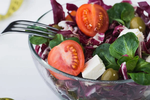トマトとチーズフェタと木のテーブルの上の緑の葉でガラスボウルに新鮮なサラダ 食事の背景 — ストック写真