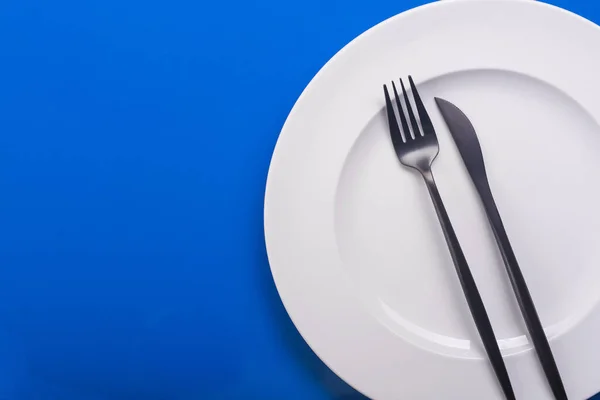 Leerer Weißer Teller Mit Messer Und Gabel Auf Blauem Tisch — Stockfoto