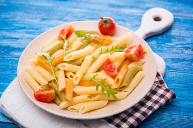Mavi ahşap bir masada domatesli lezzetli İtalyan makarnası.