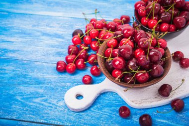 Mavi ahşap masada kırmızı taze kiraz meyvesi. Tatlı..