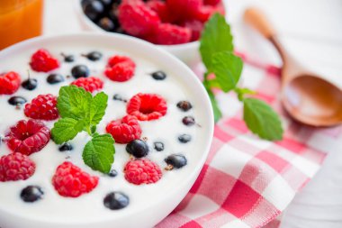 Ahududu meyveli yoğurt ve taze nane suyu, beyaz ahşap arka planda bir bardak meyve suyu.
