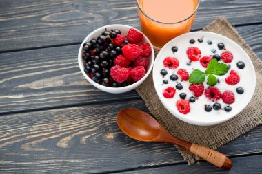 Ahududulu taze yoğurt ve ahşap masada yeşil nane. Tatlı yemek.