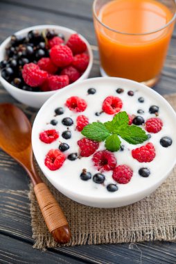 Ahududulu taze yoğurt ve ahşap masada yeşil nane. Tatlı yemek.