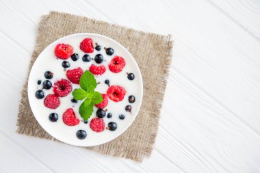 Ahşap beyaz masada ahududulu lezzetli yoğurt. tatlı kahvaltı.