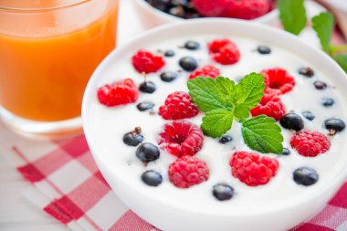 Ahududu meyveli yoğurt ve taze nane suyu, beyaz ahşap arka planda bir bardak meyve suyu.