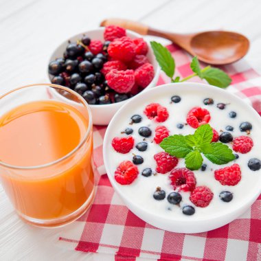 Ahududu meyveli yoğurt ve taze nane suyu, beyaz ahşap arka planda bir bardak meyve suyu.