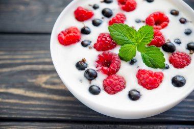 Ahududulu taze yoğurt ve ahşap masada yeşil nane. Tatlı yemek.