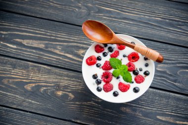 Ahududulu taze yoğurt ve ahşap masada yeşil nane. Tatlı yemek.