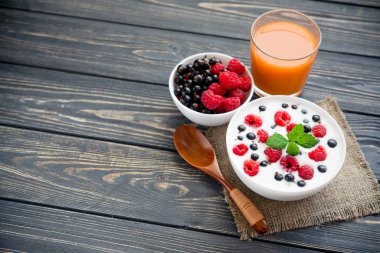 Ahududulu taze yoğurt ve ahşap masada yeşil nane. Tatlı yemek.