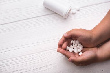 Ahşap arka planda tıbbi ilaçlar tutan bir çocuk. Çocuk tedavisi