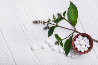 Beyaz ahşap masa üzerinde bitkisel bitki içeren doğal organik haplar. Etnosbilim konsepti