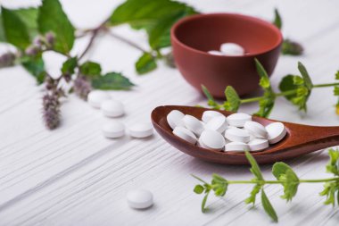 Beyaz ahşap masa üzerinde bitkisel bitki içeren doğal organik haplar. Etnosbilim konsepti