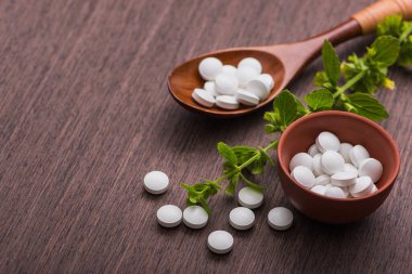 Ahşap masa üzerinde bitkisel bitki bulunan organik tıbbi haplar. Etnosbilim konsepti.