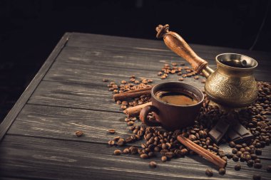 Eski kahve fincanı ve ahşap bir masada kavrulmuş fasulye ile Türk. Koyu arkaplanda klasik aroma kavramı.
